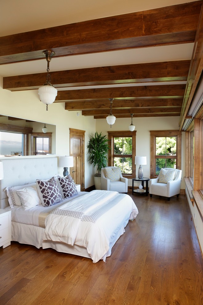 Inspiration for a mid-sized tropical master bedroom in San Francisco with white walls, dark hardwood floors, no fireplace and brown floor.