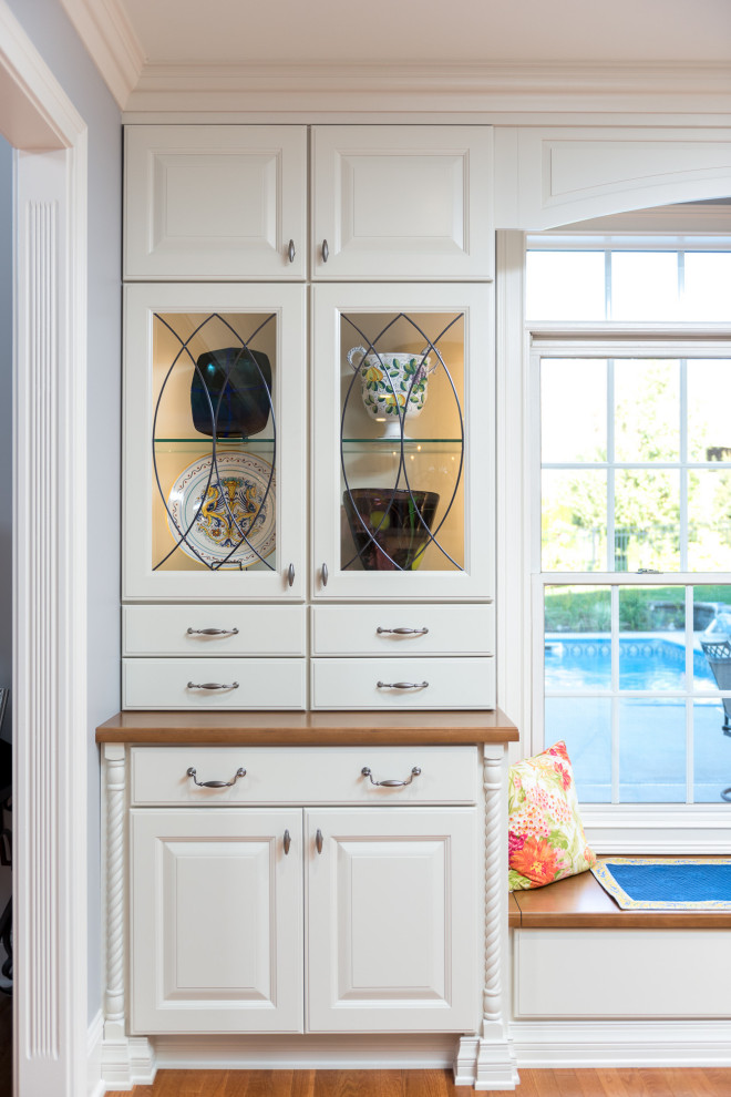 Inspiration for a large transitional single-wall light wood floor and brown floor open concept kitchen remodel with a farmhouse sink, raised-panel cabinets, white cabinets, quartz countertops, white backsplash, ceramic backsplash, stainless steel appliances, an island and white countertops