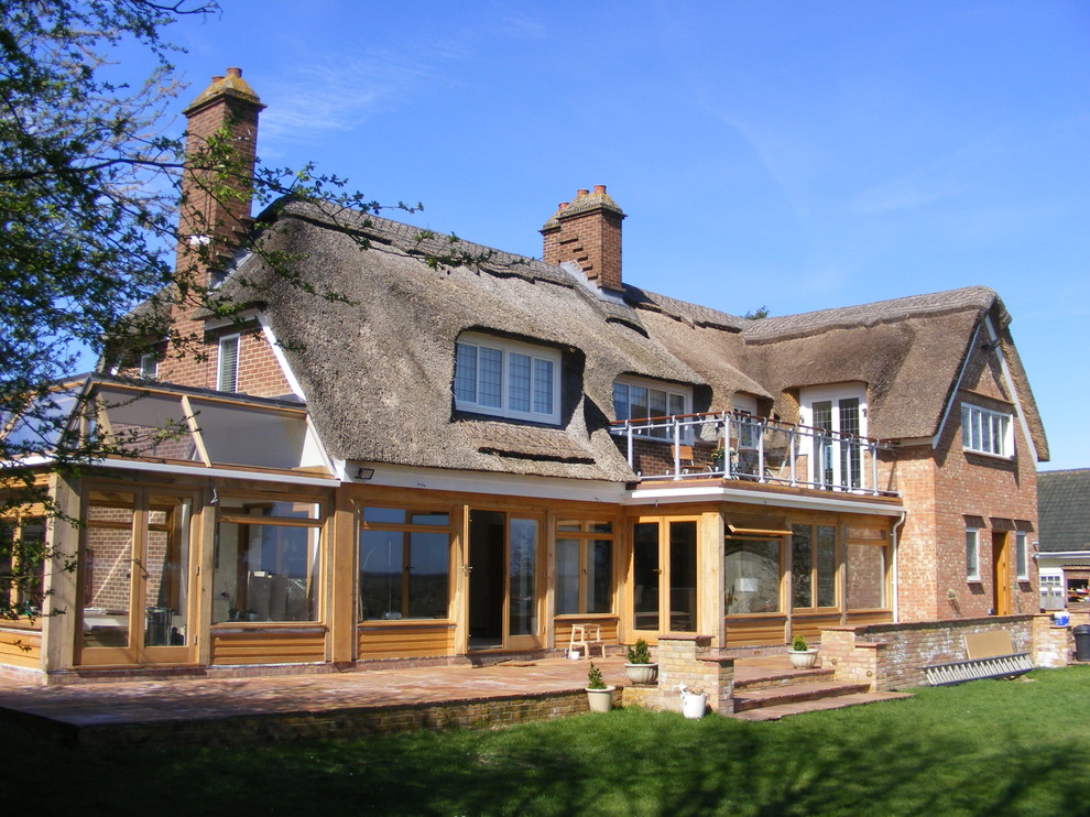 Photo of a large country two-storey brick brown house exterior in Kent with a gable roof.