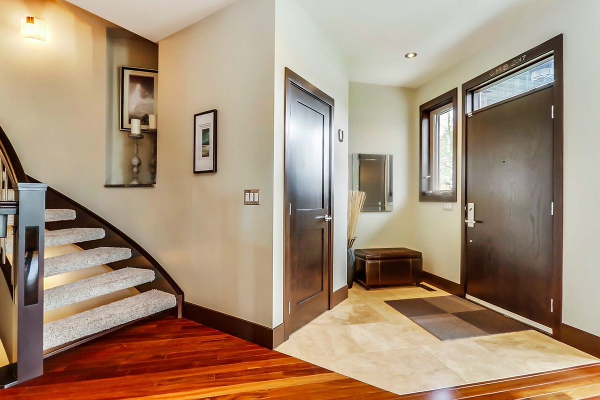 Inspiration for a mid-sized transitional medium tone wood floor front door remodel in Calgary with beige walls and a dark wood front door