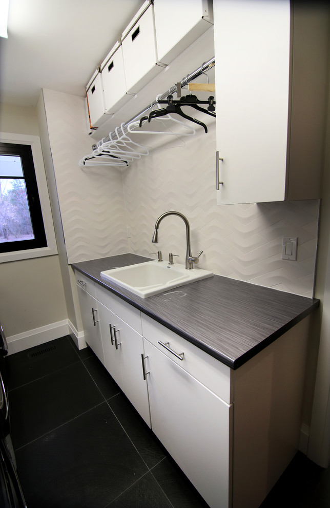 This is an example of a mid-sized transitional galley dedicated laundry room in Toronto with a drop-in sink, flat-panel cabinets, white cabinets, wood benchtops, beige walls, a side-by-side washer and dryer and grey benchtop.
