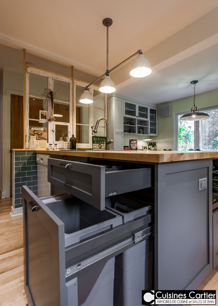 Large transitional galley medium tone wood floor open concept kitchen photo in Montreal with a single-bowl sink, shaker cabinets, gray cabinets, wood countertops, green backsplash, ceramic backsplash, white appliances and an island