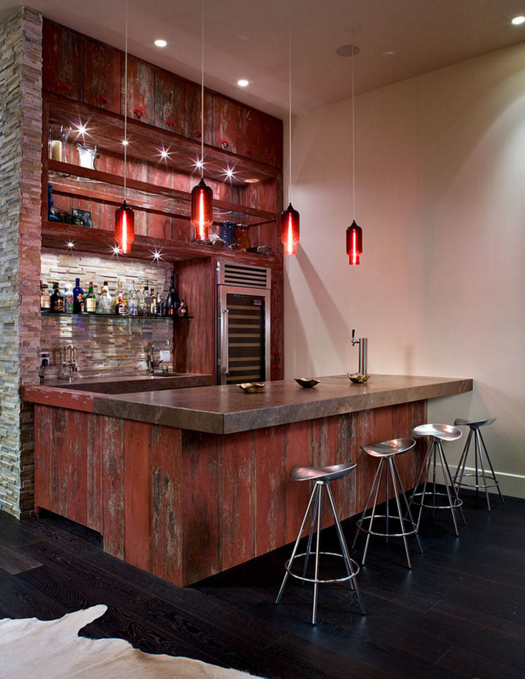 This is an example of an industrial galley seated home bar in New York with open cabinets, red cabinets, beige splashback, stone tile splashback, dark hardwood floors and black floor.