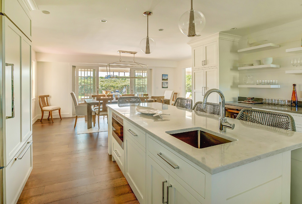 Inspiration for a large coastal l-shaped medium tone wood floor and brown floor open concept kitchen remodel with an undermount sink, shaker cabinets, white cabinets, marble countertops, stainless steel appliances and an island