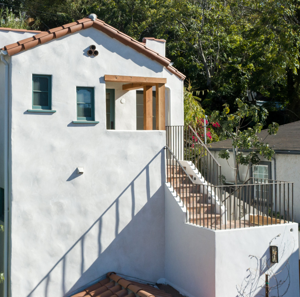 Design ideas for a mid-sized mediterranean two-storey stucco white exterior in Los Angeles with a tile roof.