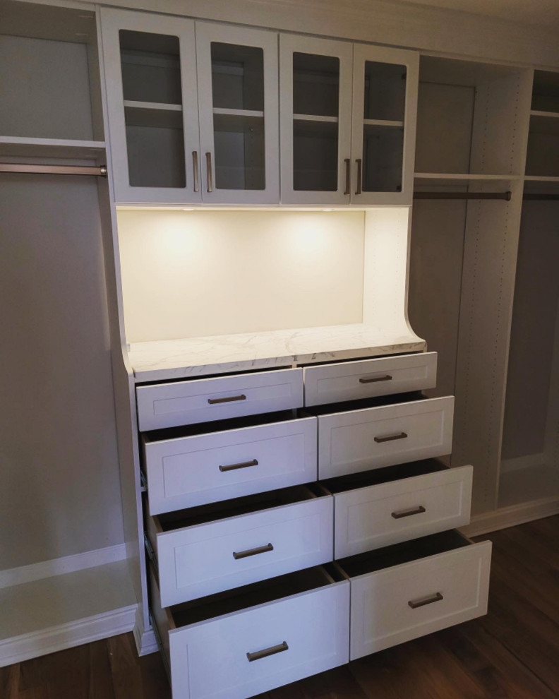 Photo of a large traditional gender-neutral walk-in wardrobe in New York with shaker cabinets, white cabinets, medium hardwood floors and brown floor.
