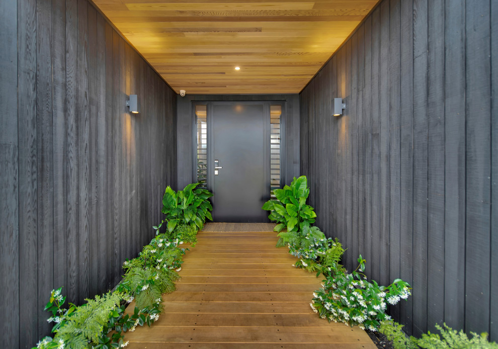 Foto de puerta principal contemporánea pequeña con paredes negras, suelo de madera en tonos medios, puerta simple, puerta negra, suelo marrón, madera y madera