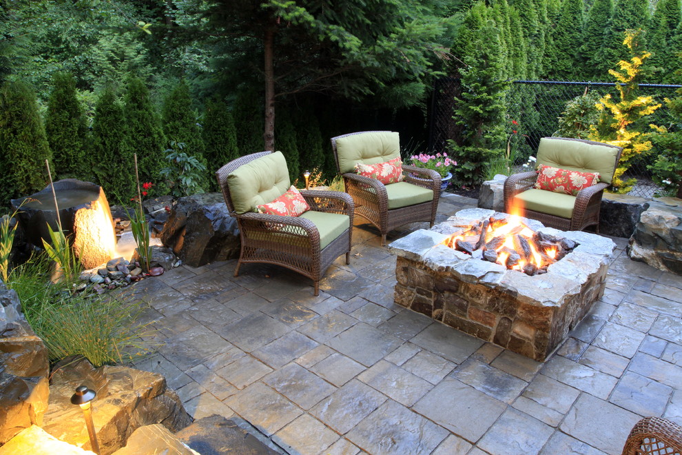 This is an example of a mid-sized traditional backyard patio in Seattle with a fire feature, natural stone pavers and no cover.
