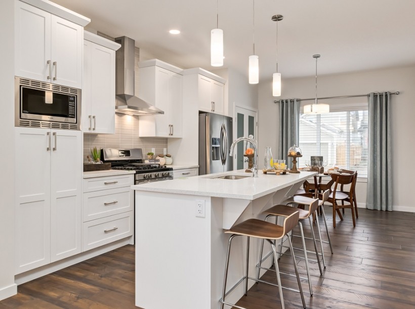 Inspiration for a large contemporary galley eat-in kitchen in Calgary with an undermount sink, white cabinets, quartz benchtops, grey splashback, ceramic splashback, stainless steel appliances, laminate floors, with island and brown floor.