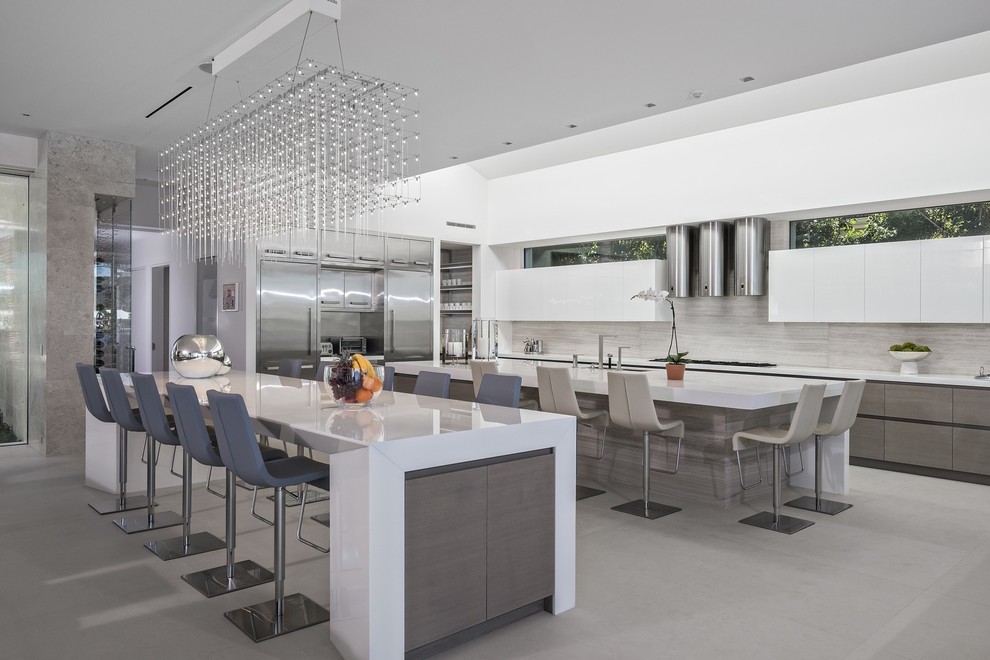 Photo of a contemporary kitchen in New York with an undermount sink, flat-panel cabinets, white cabinets, grey splashback, stainless steel appliances, multiple islands and grey floor.