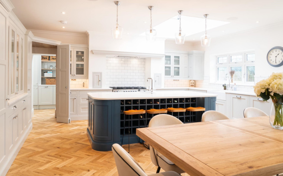 Inspiration for a large traditional u-shaped eat-in kitchen in Other with an undermount sink, louvered cabinets, grey cabinets, white splashback, porcelain splashback, stainless steel appliances, medium hardwood floors, with island, brown floor, white benchtop and vaulted.