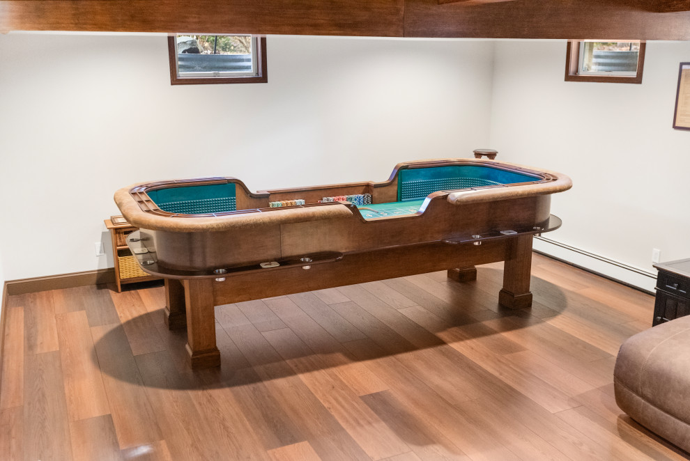 This is an example of a medium sized classic open plan games room in New York with a game room, white walls, vinyl flooring, no fireplace, a wall mounted tv, brown floors and exposed beams.