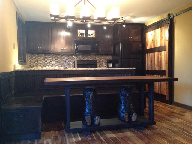 Inspiration for a small rustic galley medium tone wood floor and brown floor eat-in kitchen remodel with an undermount sink, shaker cabinets, dark wood cabinets, granite countertops, brown backsplash, glass tile backsplash, black appliances and a peninsula