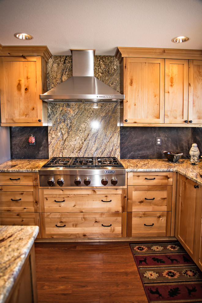 This is an example of a traditional kitchen in Portland with an undermount sink, shaker cabinets, light wood cabinets, granite benchtops, blue splashback, stone slab splashback, stainless steel appliances, medium hardwood floors and brown floor.
