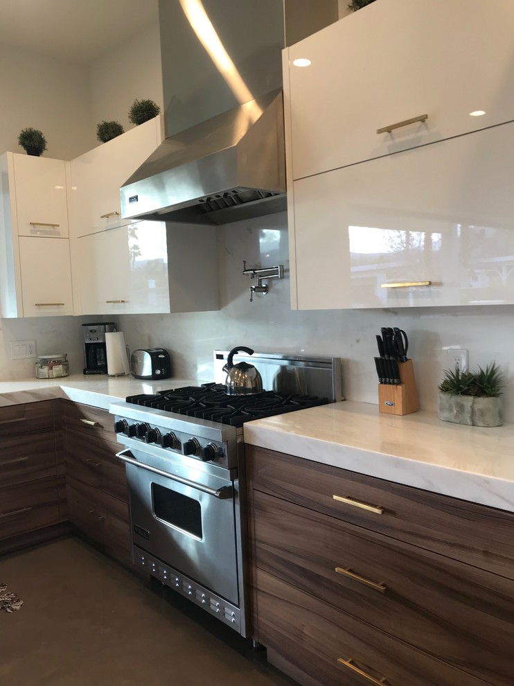 This is an example of a large modern eat-in kitchen in Other with flat-panel cabinets, granite benchtops, stainless steel appliances, concrete floors and with island.
