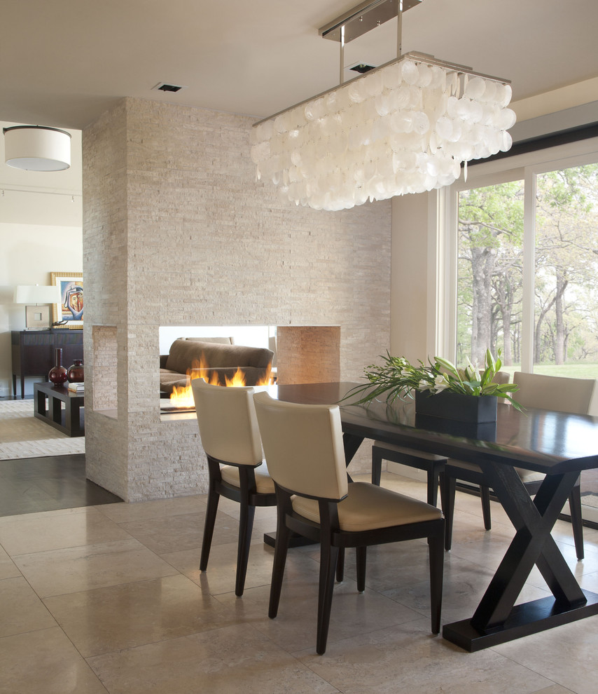 Inspiration for a contemporary dining room in Denver with a two-sided fireplace, a tile fireplace surround, travertine floors and beige floor.
