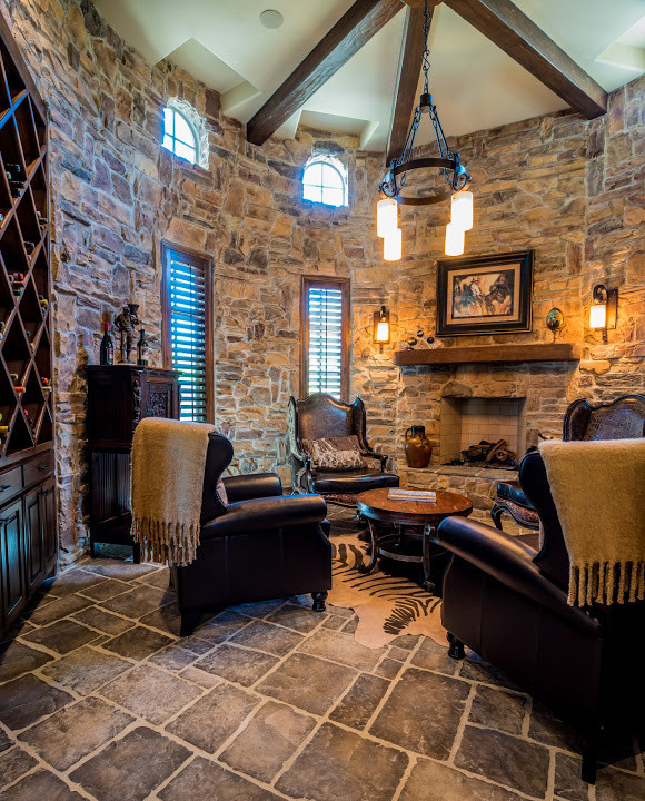 This is an example of a mid-sized mediterranean enclosed living room in Dallas with a home bar, multi-coloured walls, slate floors, a standard fireplace, a stone fireplace surround, no tv and multi-coloured floor.