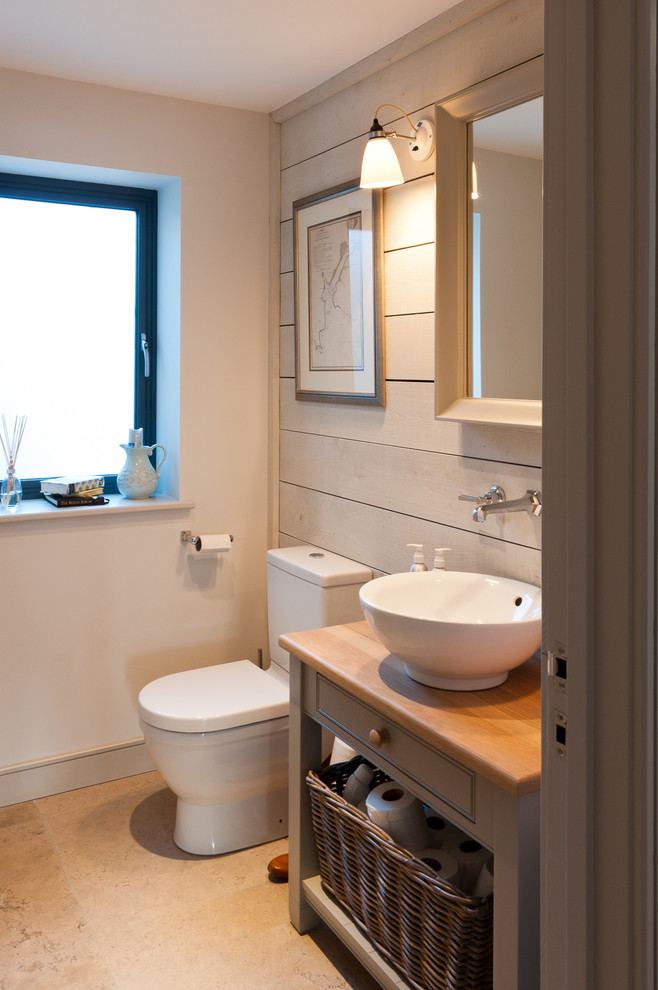 Photo of a small beach style bathroom in Devon with a vessel sink, grey cabinets, white walls, shaker cabinets, a two-piece toilet, ceramic floors, wood benchtops, beige floor and grey benchtops.