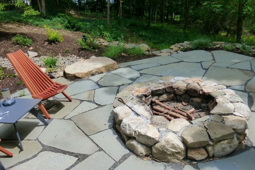 This is an example of a large country side yard full sun xeriscape for summer in New York with a fire feature and natural stone pavers.