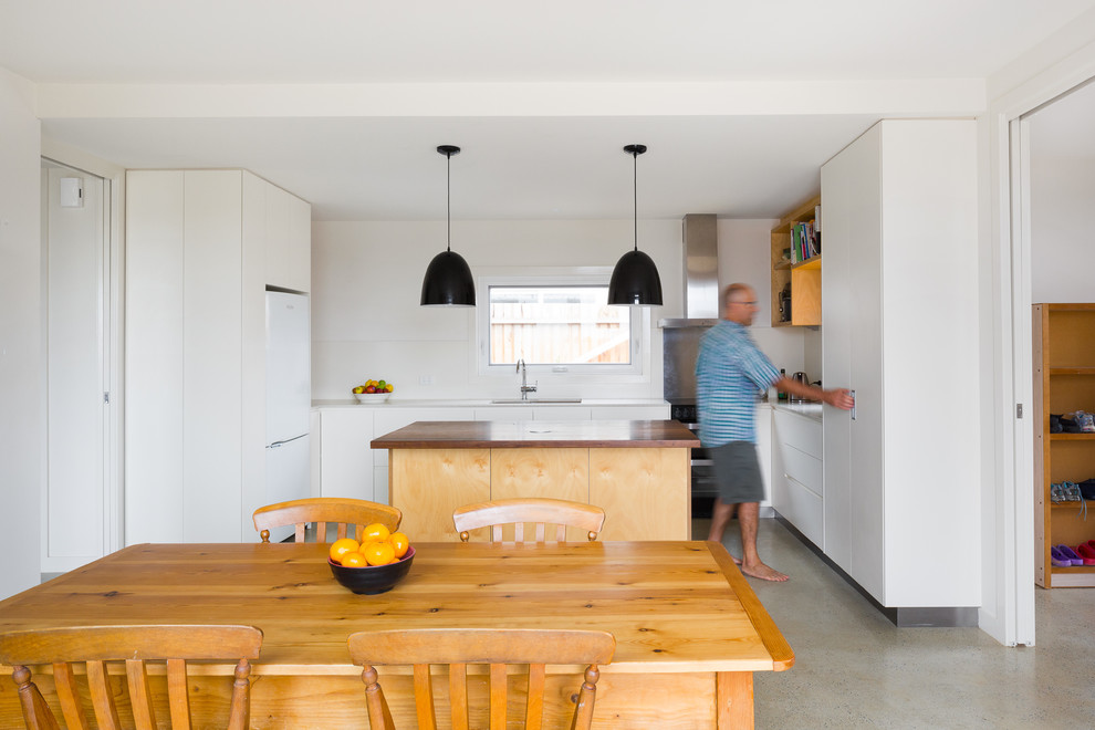 Photo of a mid-sized scandinavian u-shaped kitchen in Canberra - Queanbeyan with flat-panel cabinets, white cabinets, concrete floors and with island.