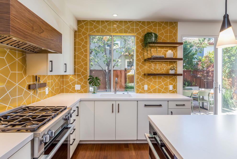 Design ideas for a mid-sized midcentury u-shaped eat-in kitchen in San Francisco with an undermount sink, flat-panel cabinets, white cabinets, quartz benchtops, yellow splashback, ceramic splashback, stainless steel appliances, medium hardwood floors, with island, brown floor, white benchtop and timber.