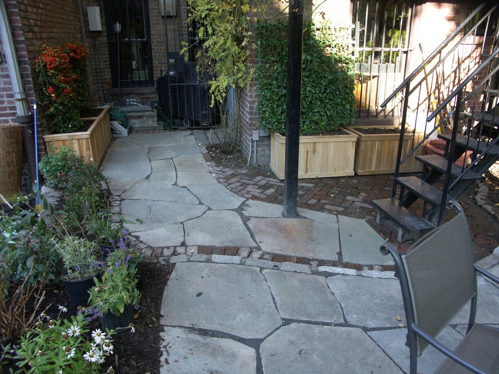 Design ideas for a mid-sized traditional courtyard patio in New York with a container garden and natural stone pavers.