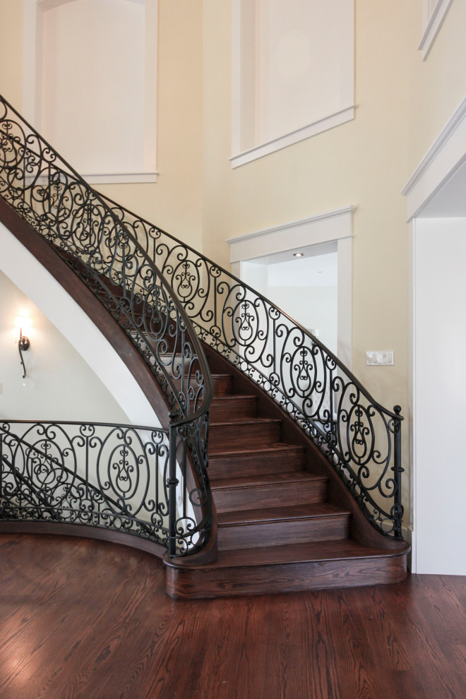 This is an example of an expansive transitional wood curved staircase in DC Metro with wood risers and metal railing.