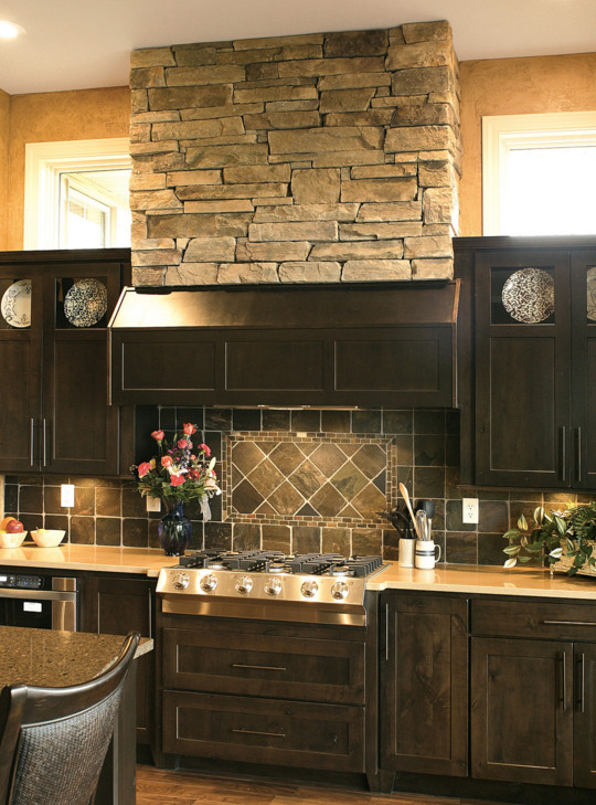 Enclosed kitchen - mid-sized rustic l-shaped medium tone wood floor and brown floor enclosed kitchen idea in Chicago with an undermount sink, recessed-panel cabinets, dark wood cabinets, quartz countertops, gray backsplash, stone tile backsplash, stainless steel appliances and an island