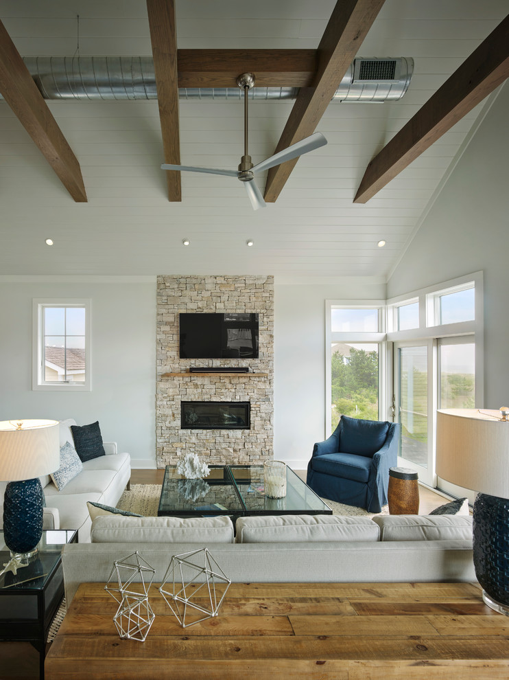 Inspiration for a mid-sized beach style open concept family room in Other with grey walls, medium hardwood floors, a ribbon fireplace, a stone fireplace surround, a wall-mounted tv and brown floor.