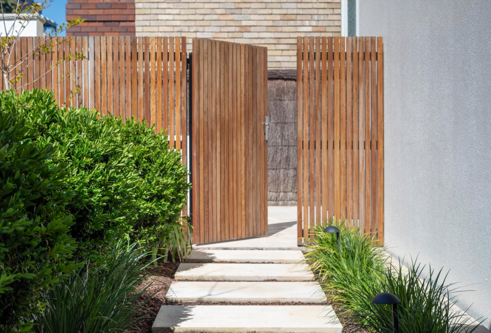 Inspiration pour un petit jardin arrière design avec des pavés en pierre naturelle et une clôture en bois.