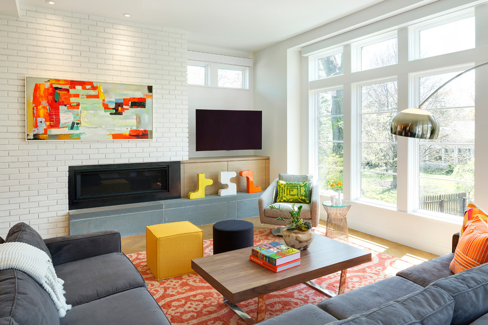 This is an example of a midcentury open concept family room in Minneapolis with white walls, light hardwood floors, a ribbon fireplace, a metal fireplace surround and a wall-mounted tv.