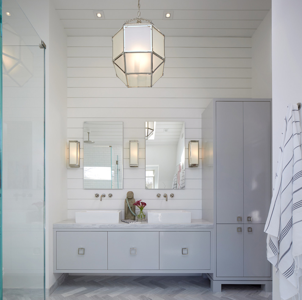This is an example of a large modern master bathroom in New York with a two-piece toilet, white tile, subway tile, white walls, marble floors, a pedestal sink, flat-panel cabinets, grey cabinets, marble benchtops, grey floor and a curbless shower.