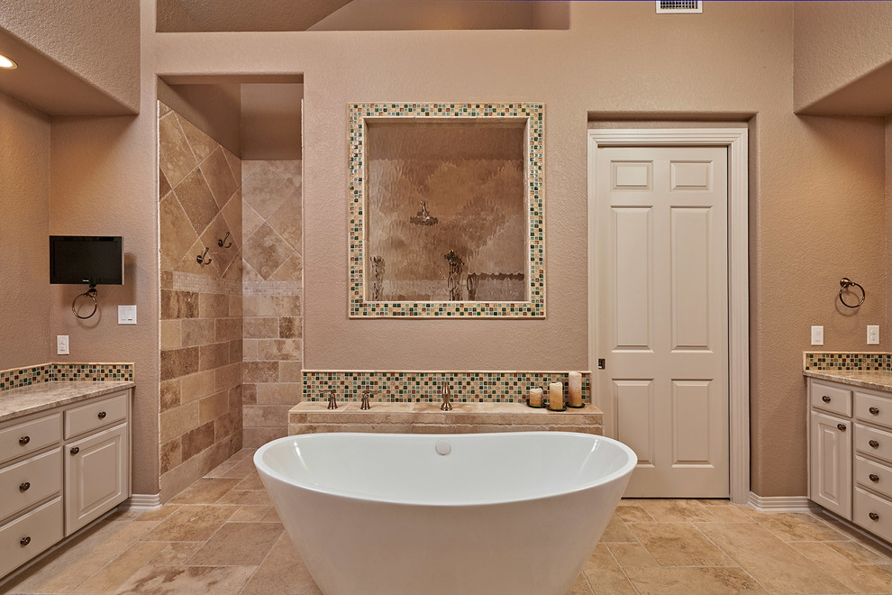 This is an example of a large traditional master bathroom in Houston with shaker cabinets, white cabinets, a freestanding tub, an open shower, a one-piece toilet, beige tile, porcelain tile, beige walls, porcelain floors, an undermount sink and granite benchtops.