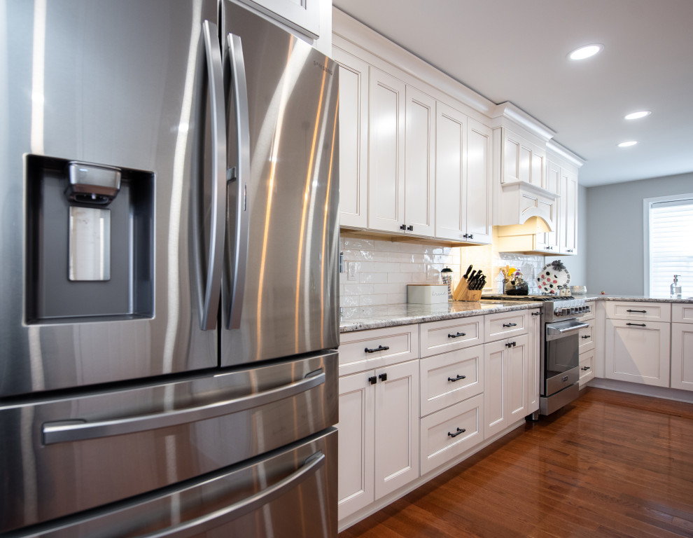 Photo of a large transitional l-shaped separate kitchen in Philadelphia with an undermount sink, beaded inset cabinets, beige cabinets, granite benchtops, white splashback, ceramic splashback, stainless steel appliances, dark hardwood floors, with island, brown floor and white benchtop.