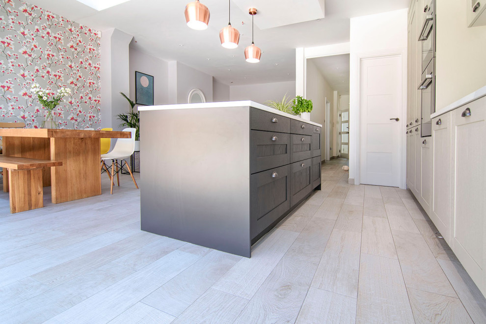 This is an example of a mid-sized traditional single-wall open plan kitchen in London with an undermount sink, shaker cabinets, grey cabinets, quartzite benchtops, with island and white benchtop.