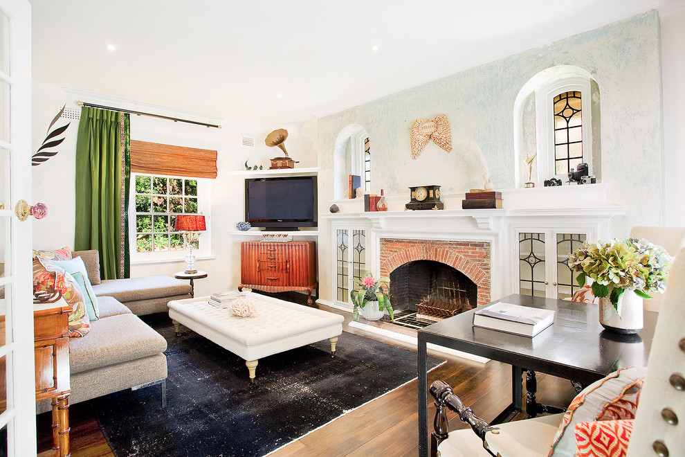Eclectic enclosed living room in Los Angeles with white walls, a standard fireplace, a brick fireplace surround, a built-in media wall and medium hardwood floors.