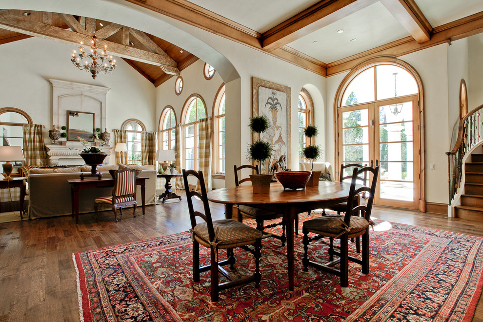 Design ideas for an expansive mediterranean dining room in Dallas with medium hardwood floors, a standard fireplace, a stone fireplace surround and brown floor.