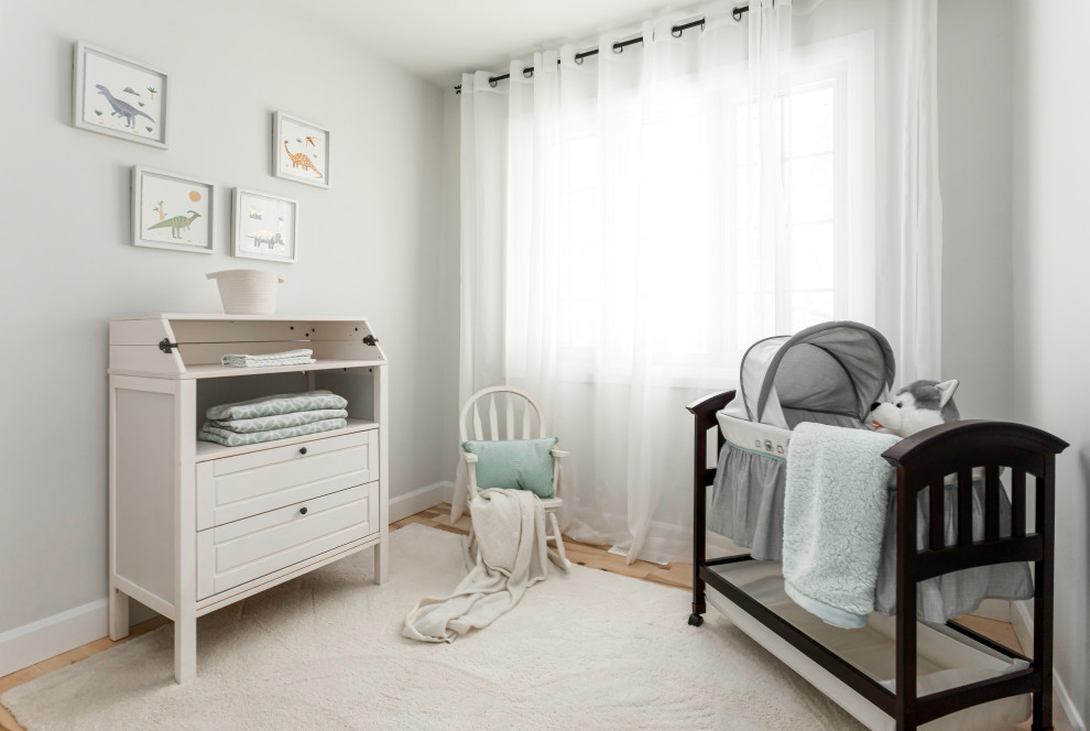 Immagine di una piccola cameretta per neonati neutra country con pareti bianche, parquet chiaro e pavimento marrone