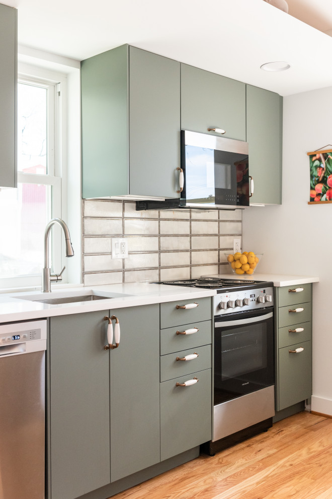 Photo of a contemporary galley kitchen/diner in DC Metro with a submerged sink, flat-panel cabinets, green cabinets, quartz worktops, grey splashback, stone tiled splashback, stainless steel appliances, bamboo flooring, an island, brown floors, white worktops and a vaulted ceiling.