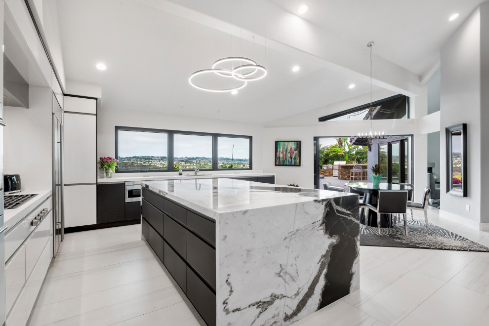 Example of a mid-sized trendy porcelain tile, white floor and exposed beam eat-in kitchen design in Orange County with an undermount sink, flat-panel cabinets, black cabinets, marble countertops, white backsplash, marble backsplash, stainless steel appliances, an island and white countertops