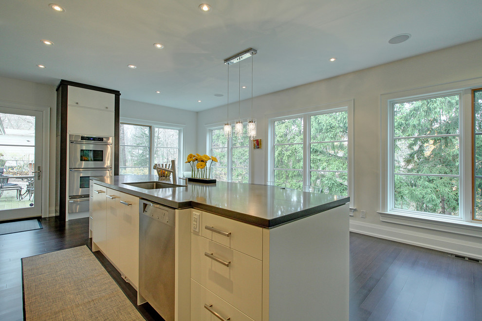 Inspiration for a large contemporary galley eat-in kitchen in Toronto with an undermount sink, flat-panel cabinets, white cabinets, solid surface benchtops, stainless steel appliances, dark hardwood floors and with island.