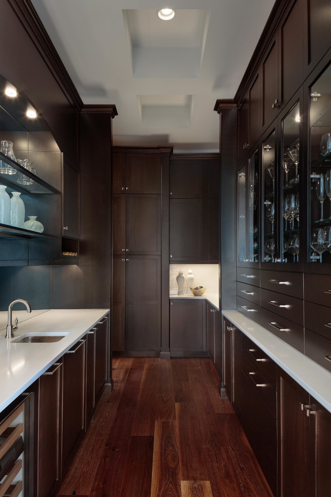 Inspiration for an expansive transitional galley wet bar in Miami with an undermount sink, recessed-panel cabinets, dark wood cabinets, quartzite benchtops, mirror splashback, dark hardwood floors, brown floor and white benchtop.