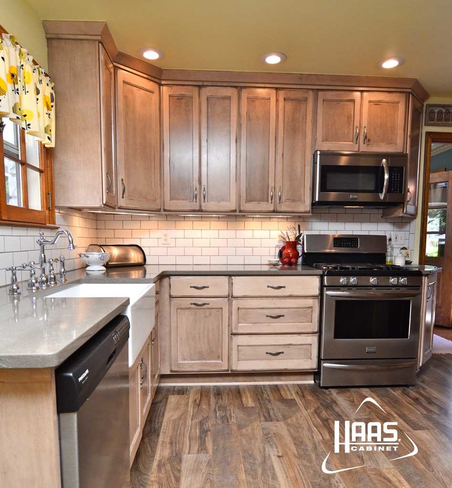 This is an example of a mid-sized country kitchen in Louisville with a farmhouse sink, recessed-panel cabinets, light wood cabinets, white splashback, subway tile splashback, stainless steel appliances and medium hardwood floors.