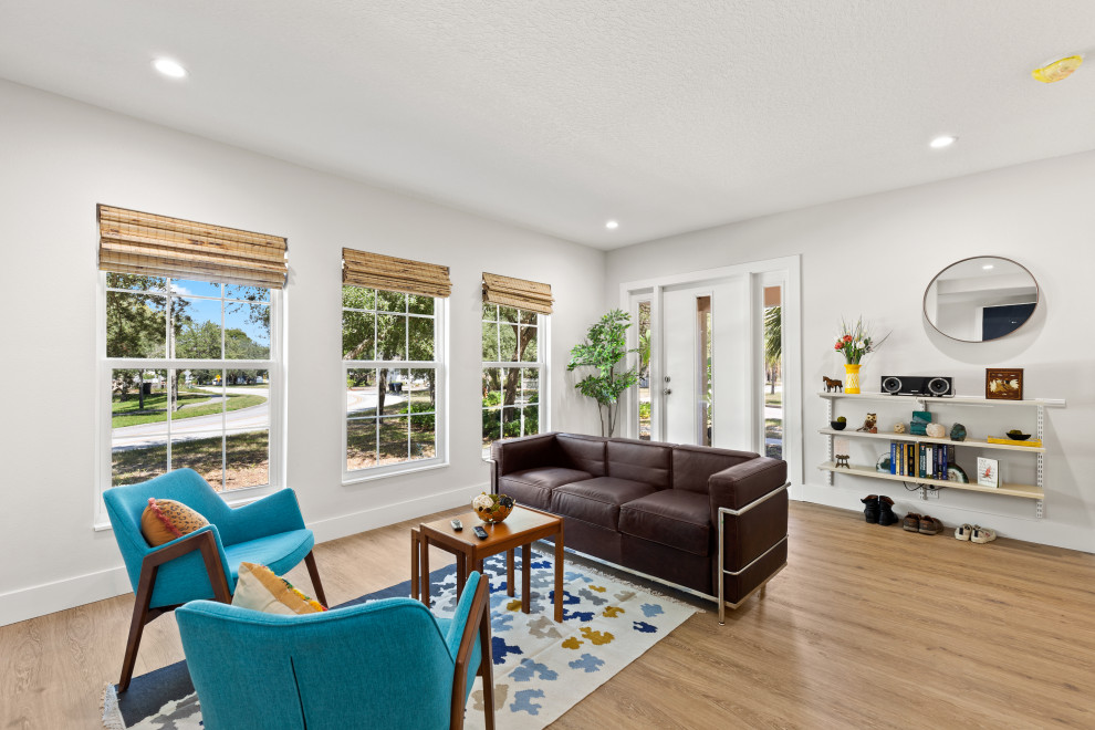 This is an example of a small contemporary living room in Tampa with white walls, light hardwood floors and beige floor.
