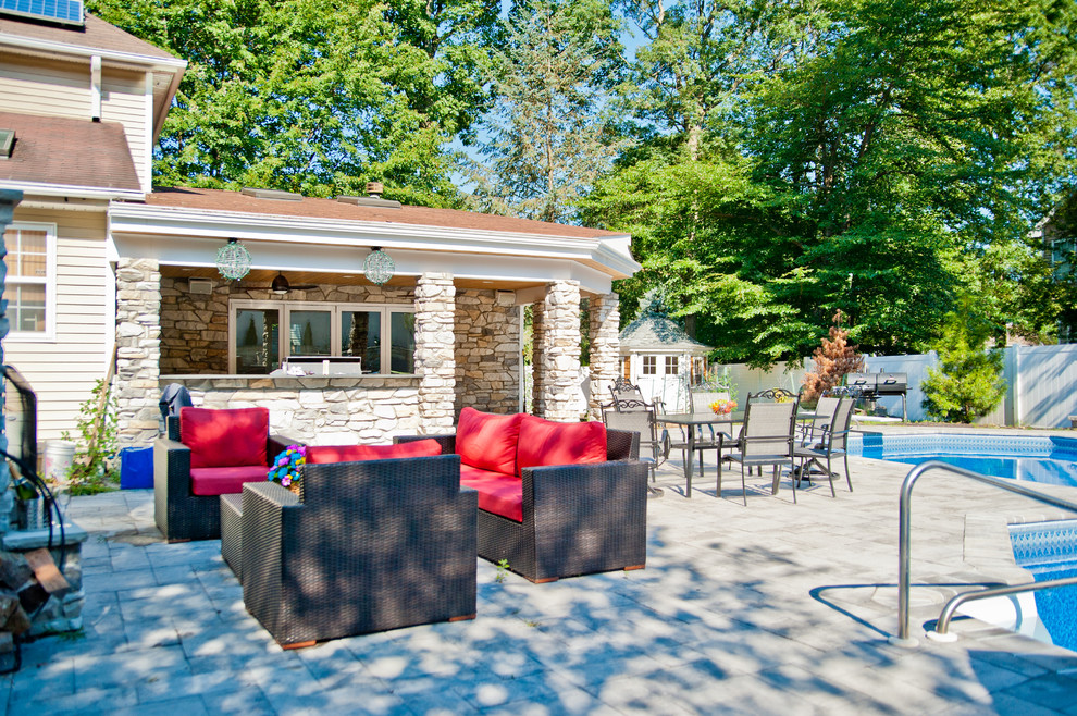 Photo of a mid-sized transitional side yard custom-shaped natural pool in New York with a pool house and natural stone pavers.