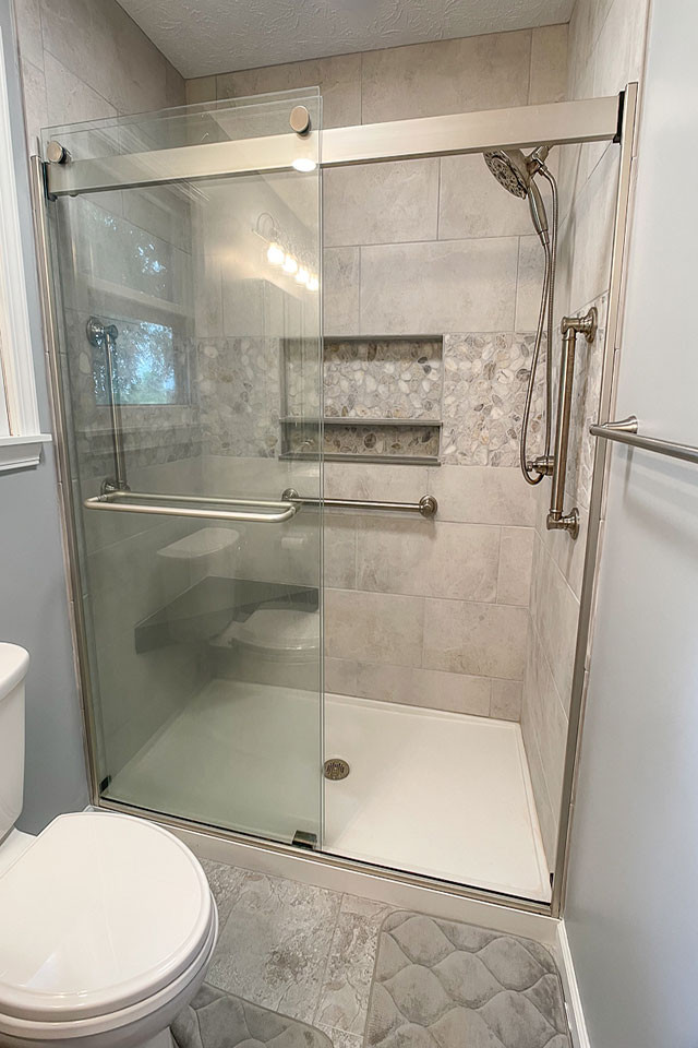 Photo of a mid-sized transitional 3/4 bathroom in Other with recessed-panel cabinets, grey cabinets, an alcove shower, a two-piece toilet, gray tile, porcelain tile, grey walls, vinyl floors, an undermount sink, marble benchtops, grey floor, a sliding shower screen, grey benchtops, a niche, a single vanity and a built-in vanity.