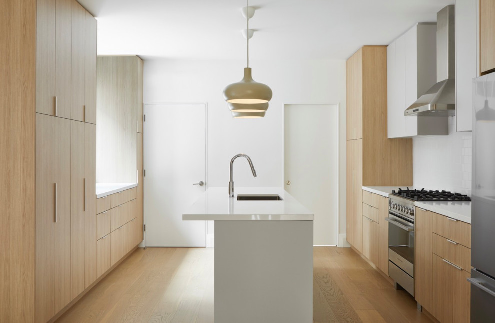 Large transitional galley medium tone wood floor and brown floor open concept kitchen photo in Toronto with an undermount sink, flat-panel cabinets, light wood cabinets, quartz countertops, white backsplash, ceramic backsplash, stainless steel appliances, an island and white countertops