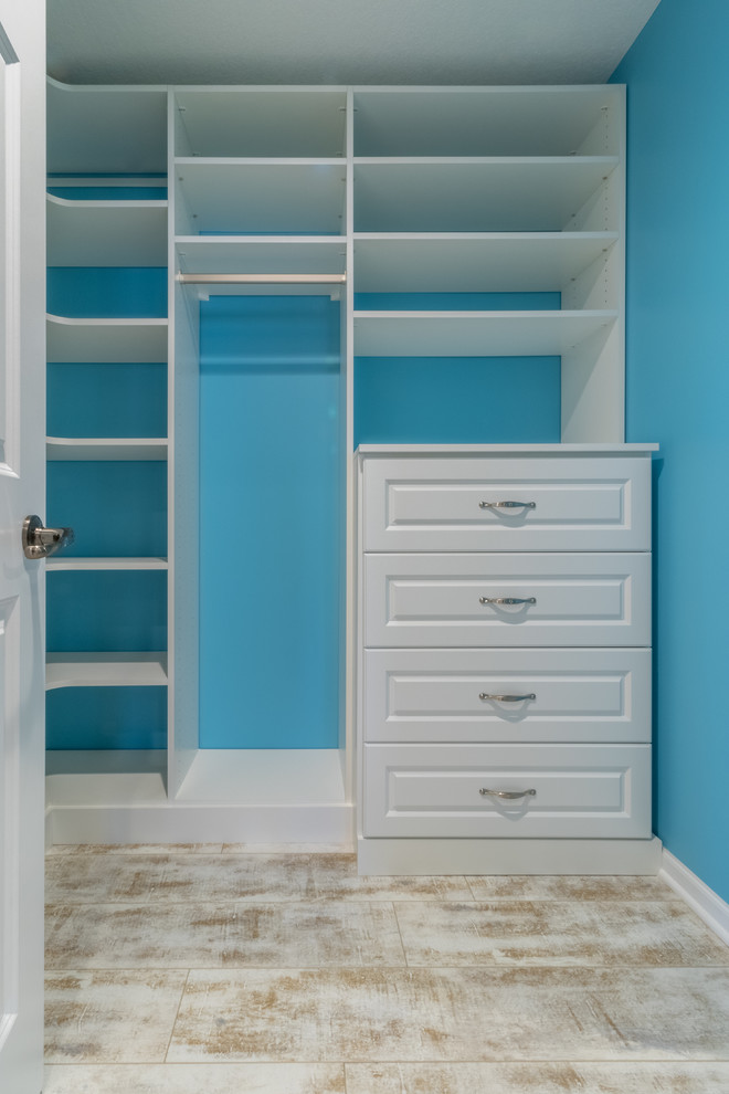 Design ideas for a mid-sized traditional gender-neutral walk-in wardrobe in Minneapolis with raised-panel cabinets, white cabinets and vinyl floors.