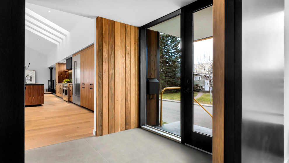 Modernes Foyer mit weißer Wandfarbe, Porzellan-Bodenfliesen, Einzeltür, Haustür aus Glas, grauem Boden und Holzwänden in Calgary