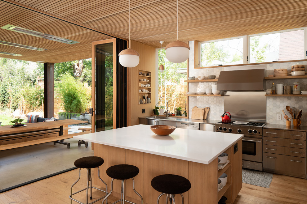 Design ideas for a midcentury kitchen in Denver with an integrated sink, open cabinets, stainless steel benchtops, metallic splashback, stainless steel appliances, light hardwood floors and with island.